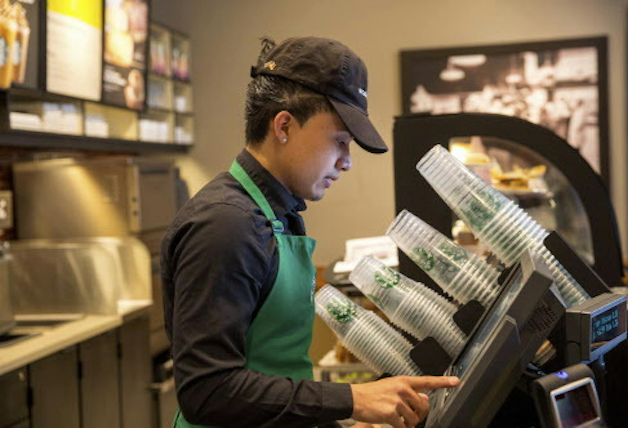 Michael Bojorquez Echevarria, a barista at Starbucks who works 60 hours at week at the company while pursuing a degree in sociology, works his early morning shift in Canoga Park, Calif., June 12, 2014. Through an unusual arrangement with Arizona State University, Starbucks will provide free, online college education to thousands of its workers -- without requiring they remain with the company. (Monica Almeida/The New York Times)
