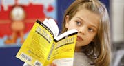 In this Nov. 29, 2016 photo, Erin Egan, a third grade student listens to retired attorney Ted Utchen who donated dictionaries to students at Park View