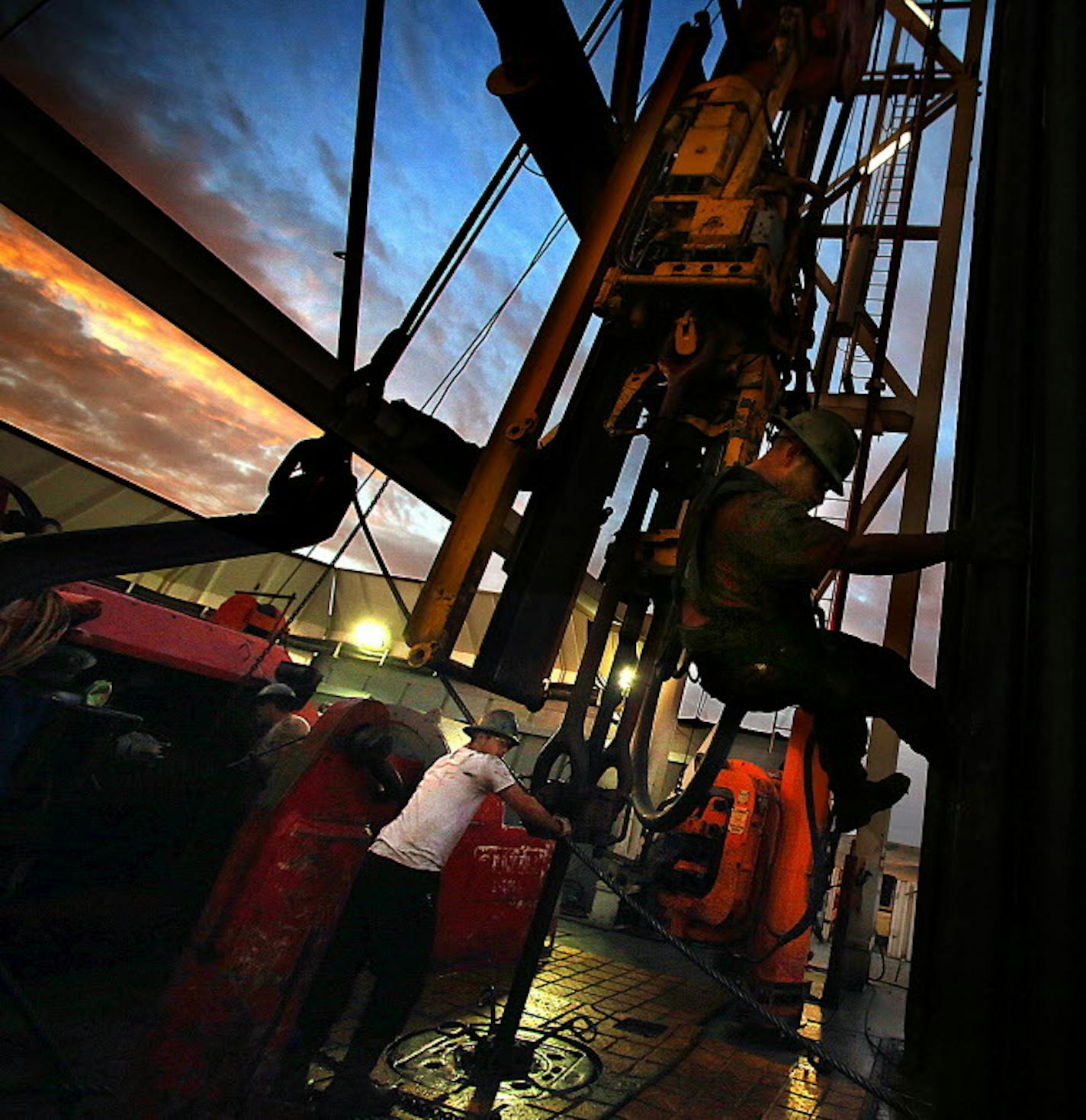 Derrick hand Scott Berreth (right) rappelled through the drilling rig structure as the crew prepared to restart machinery after some repairs had been made earlier in the morning. ] (JIM GEHRZ/STAR TRIBUNE) / December 17, 2013, Watford City, ND Men work around the clock at Raven Rig No. 1 near Watford City, one of nearly 200 towering oil rigs in the Bakken.