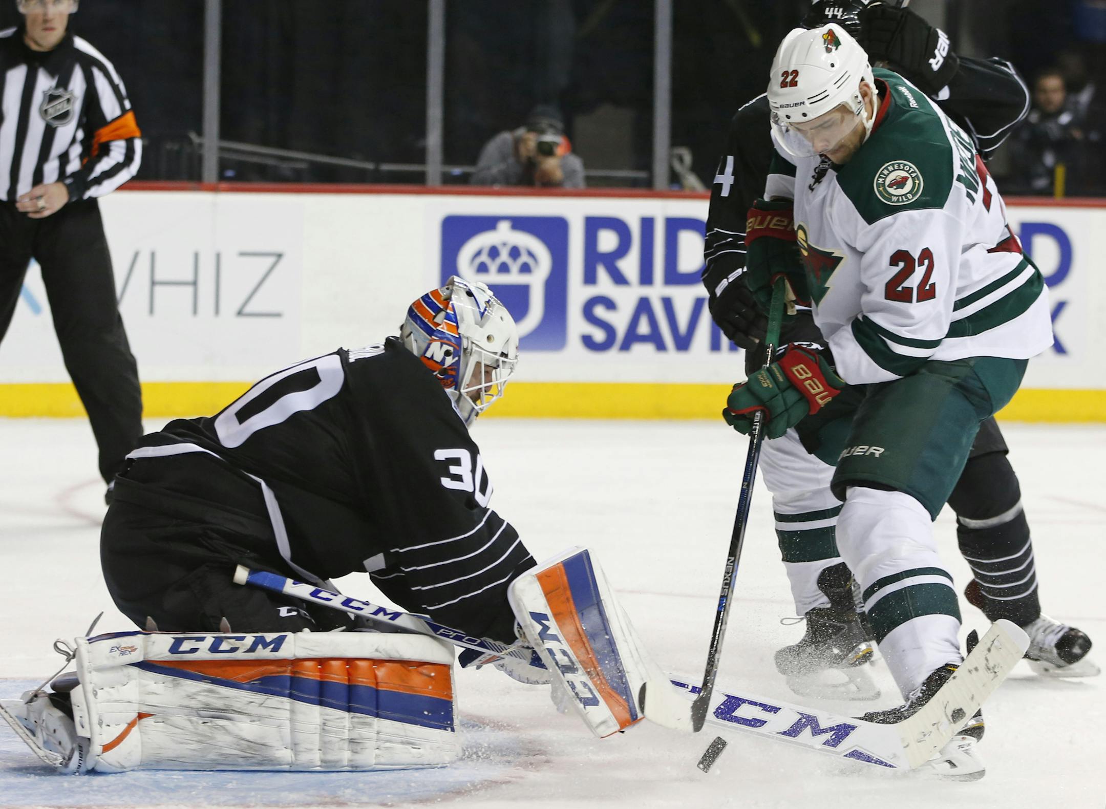 New York Islanders goalie Jean-Francois Berube (30) makes a save as New York Islanders defenseman Calvin de Haan (44) tries to defend Minnesota Wild right wing Nino Niederreiter (22) of Switzerland in the the third period of an NHL hockey game in New York, Tuesday, Feb. 2, 2016. Niderreiter scored later in the period, but the Islanders defeated the Wild 5-3. (AP Photo/Kathy Willens)