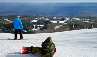 Snowboarders take a rest, and a big view of Lake Superior, near the Summit Chalet on the top of Lutsen's Moose Mountain.
