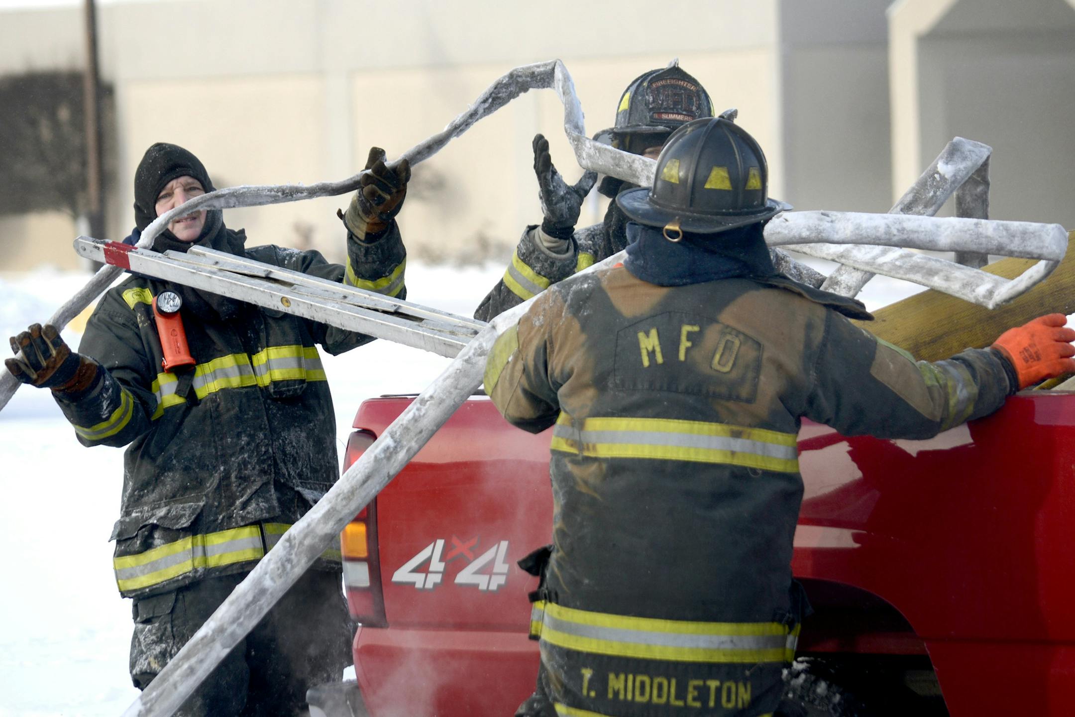 Firefighters attempt to pack up a frozen hose after fighting a fire at the Courtesy Economy Inn in Marion, Ind., on Friday, Jan. 9, 2015. Unseasonably cold conditions made fighting the fire more challenging. (AP Photo/The Chronicle-Tribune, Jeff Morehead)
