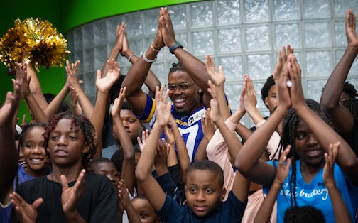 Vikings wide receiver KJ Osborn is swarmed by kids before outfitting more than 100 kids with new backpacks and school supplies, including socks with his face on them, at the Jerry Gamble Boys and Girls Club in Minneapolis, Minn., on Friday, Sept. 8, 2023. ] SHARI L. GROSS • shari.gross@startribune.com