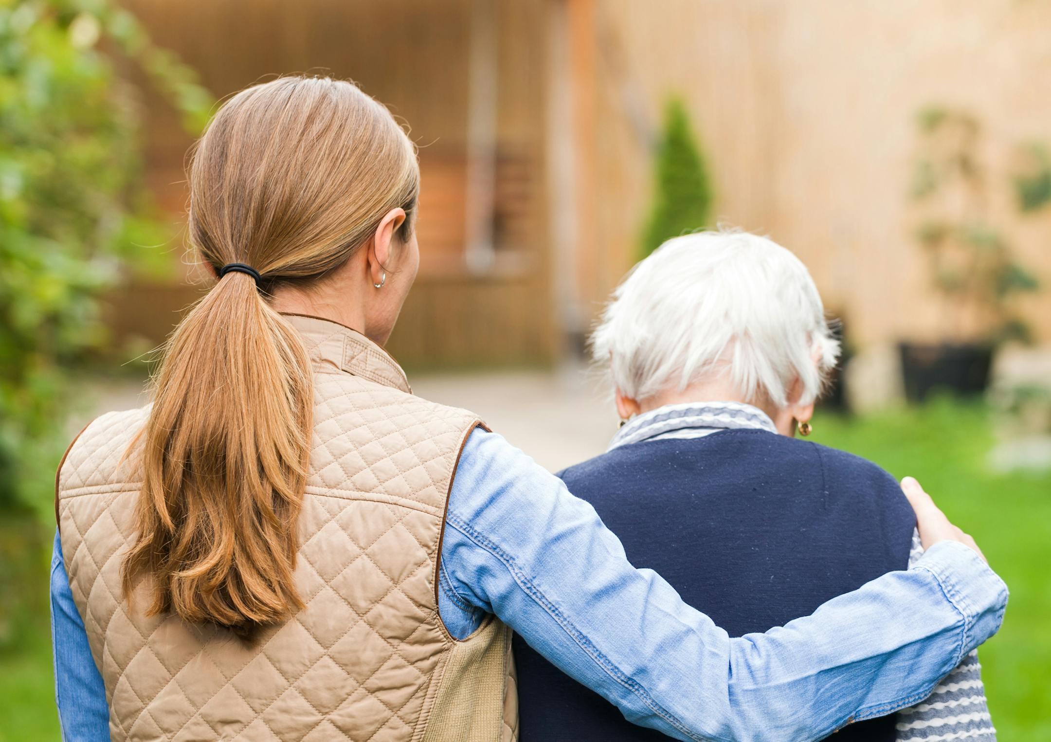 Young carer walking with the elderly woman in the park