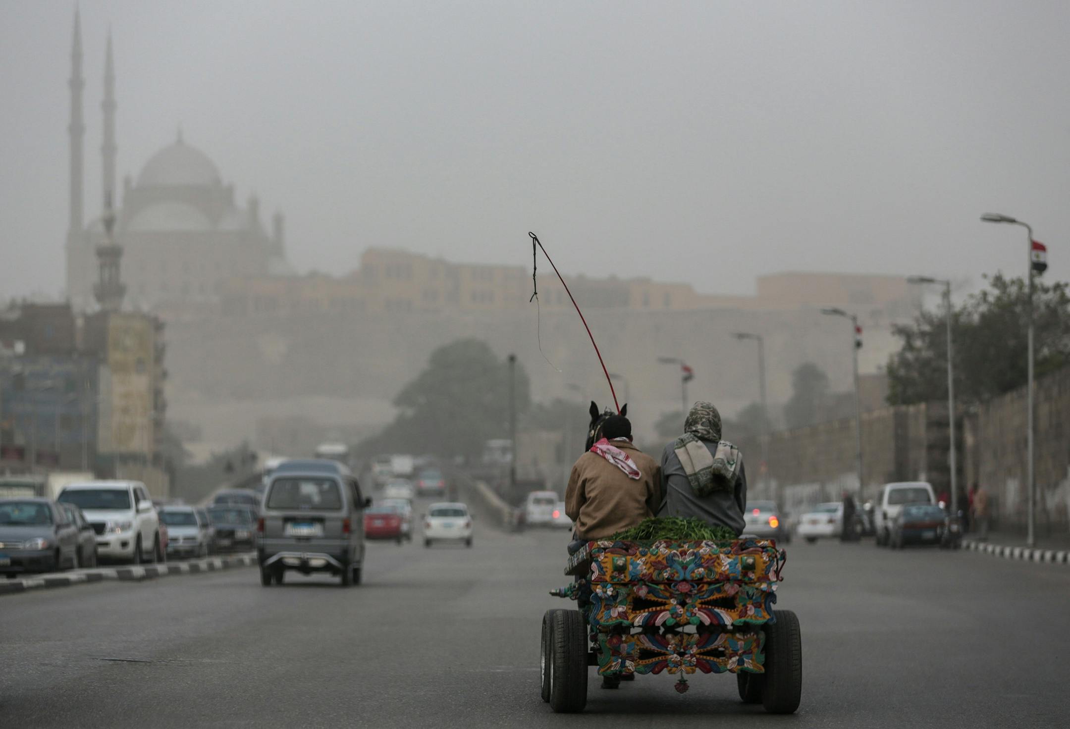 A donkey pulls a cart on one of Cairo's main roads during a sandstorm that hit the city and other parts of Egypt on Tuesday, Jan. 6, 2015. Wintry weather is striking across the Middle East, bringing cold weather to Syrian refugees in Lebanon and a blanketing sandstorm in Cairo.(AP Photo/Mosa'ab Elshamy)