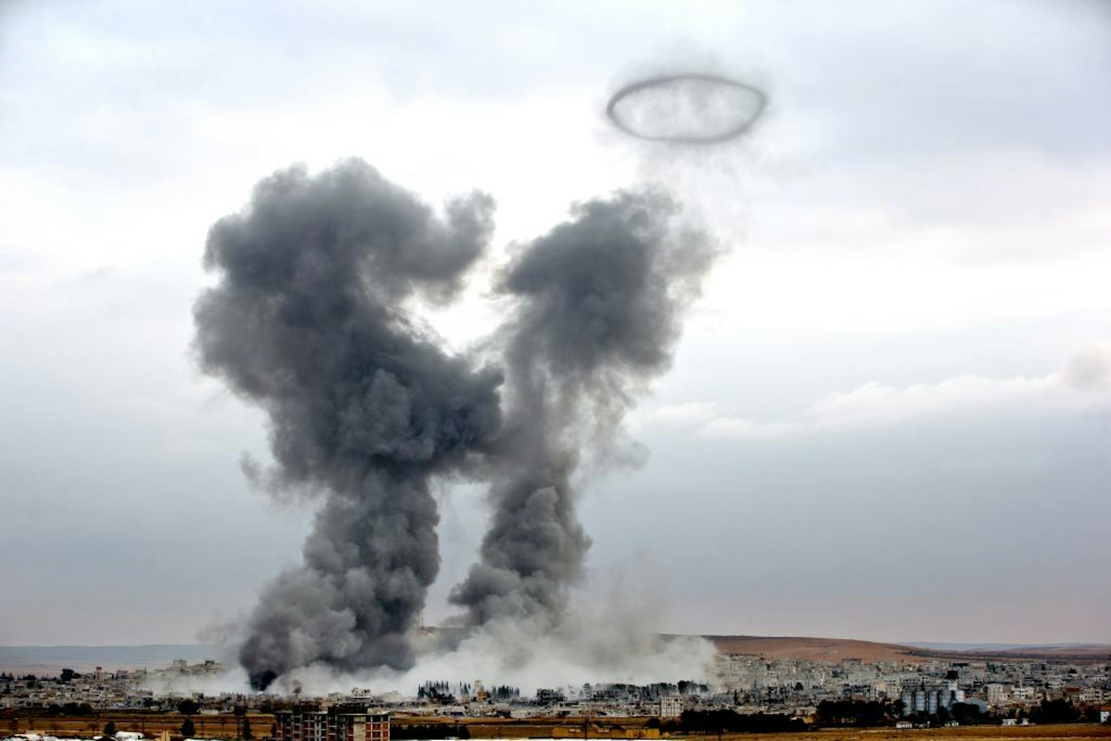 Smoke rises from the Syrian city of Kobani, following airstrikes by the US led coalition, seen from a hilltop outside Suruc, on the Turkey-Syria border Monday, Nov. 17, 2014. Kobani, also known as Ayn Arab, and its surrounding areas, has been under assault by extremists of the Islamic State group since mid-September and is being defended by Kurdish fighters.