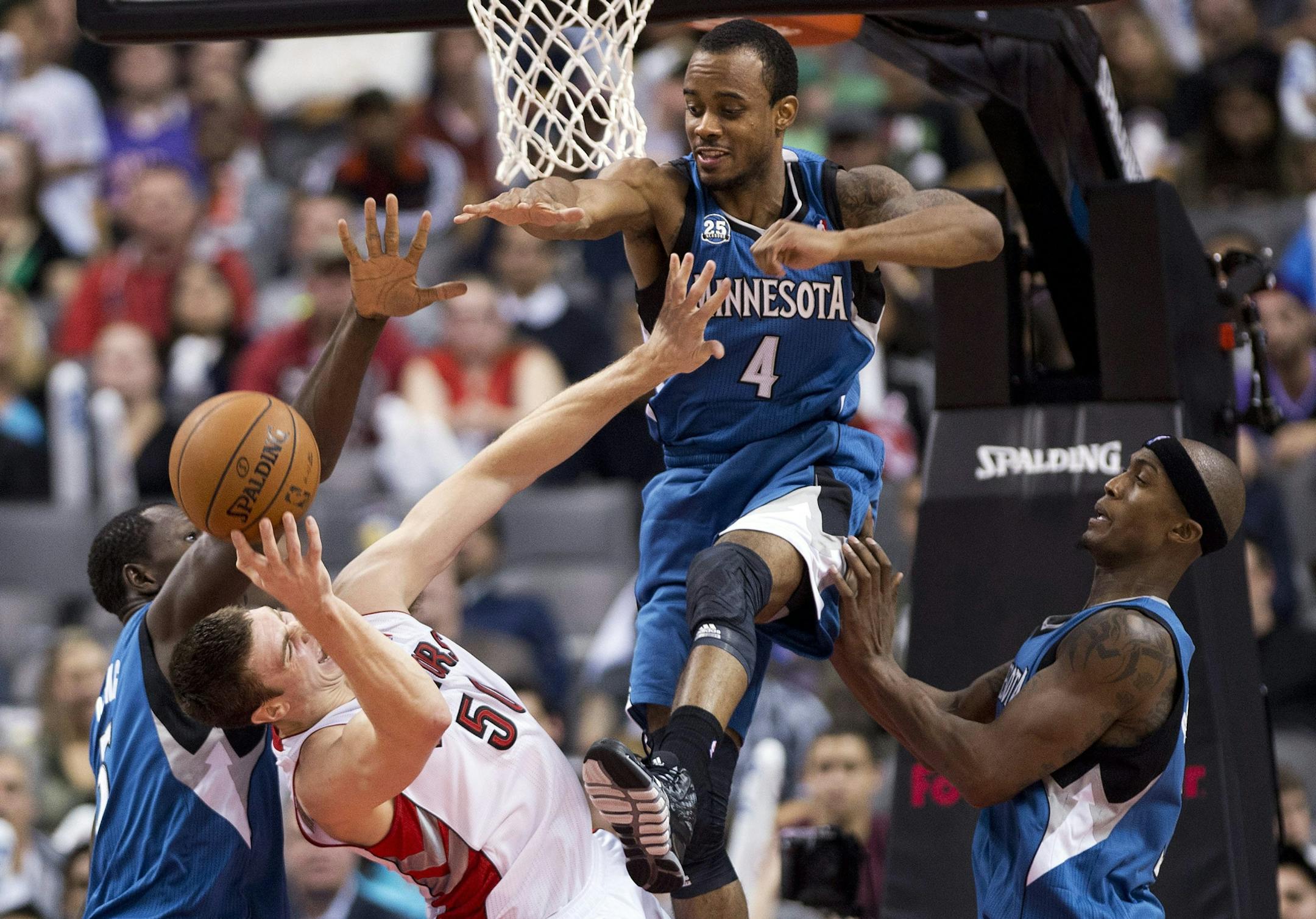 Timberwolves teammates Gorgui Dieng, left, Lorenzo Brown, second from right, and Dante Cunningham, right, strip the ball from Toronto Raptors Tyler Hansbrough during the second half of an NBA preseason basketball game in Toronto on Wednesday, Oct. 9, 2013.