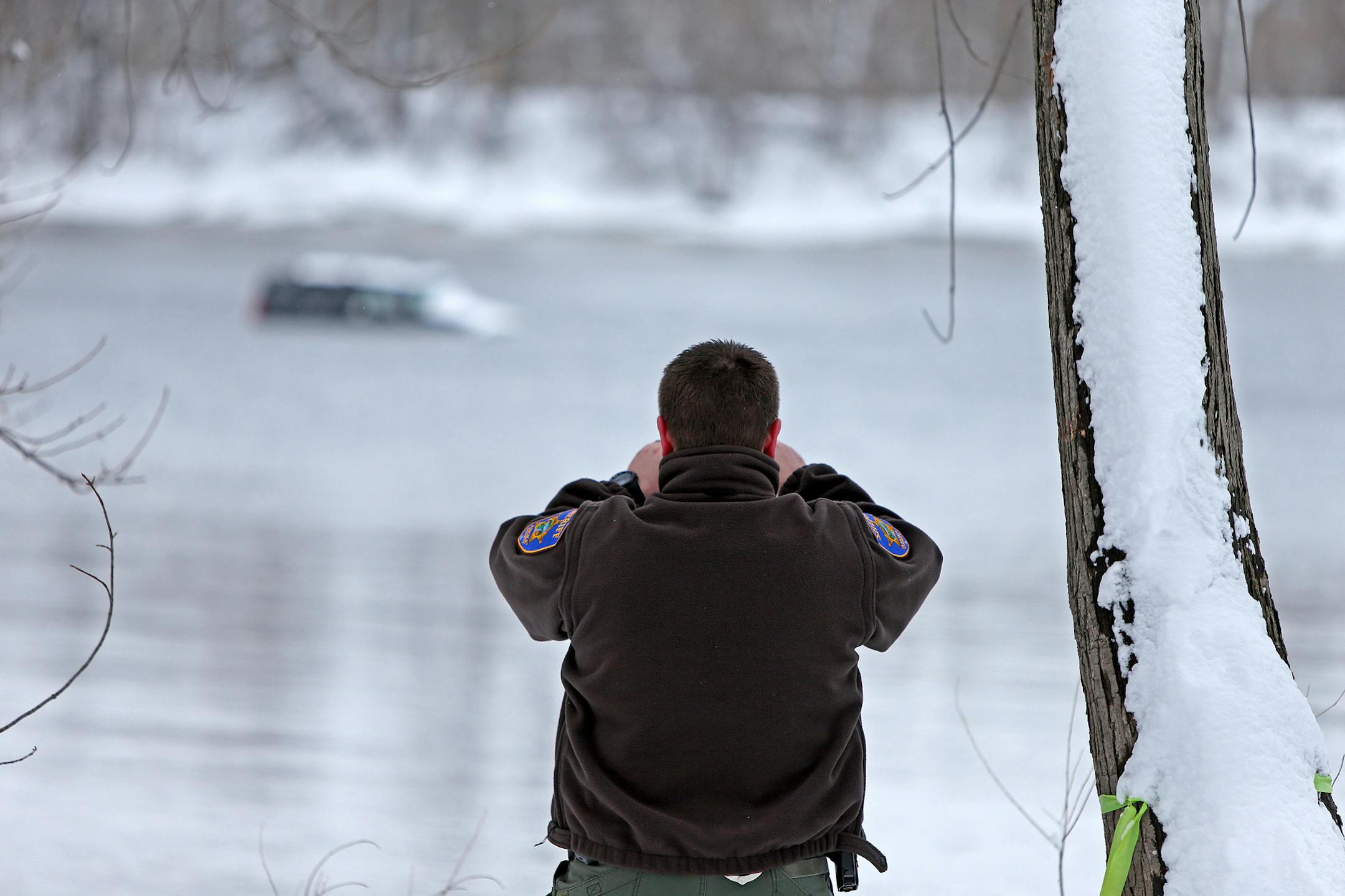 Mike Schantzen of the Anoka County Sheriff Department, took pictures near the area where a car went into the river, Friday, April 4, 2014 in Ramsey.