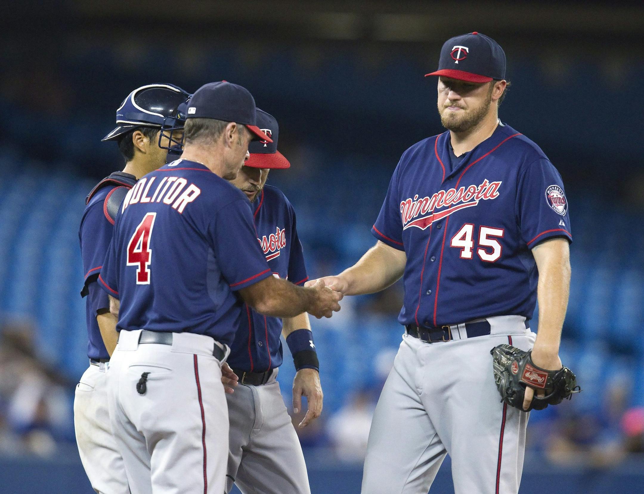Minnesota Twins' manager Paul Molitor, left, takes starting pitcher Phil Hughes out the game during the sixth inning of a baseball game against the Toronto Blue Jays, Tuesday, Aug. 4, 2015 in Toronto. (Fred Thornhill/The Canadian Press via AP) MANDATORY CREDIT
