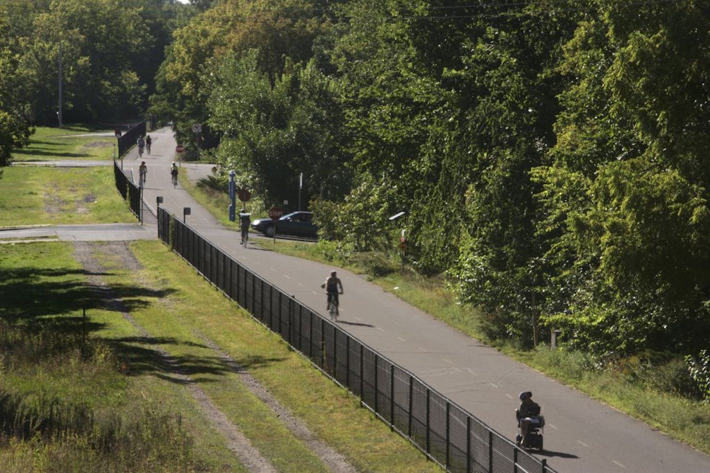 Bike commuters and recreational riders cruise thru the stop signs on the Greenway Parkway in Minneapolis, MN. Looking down from Hennepin Avenue onto the Greenway Parkway.