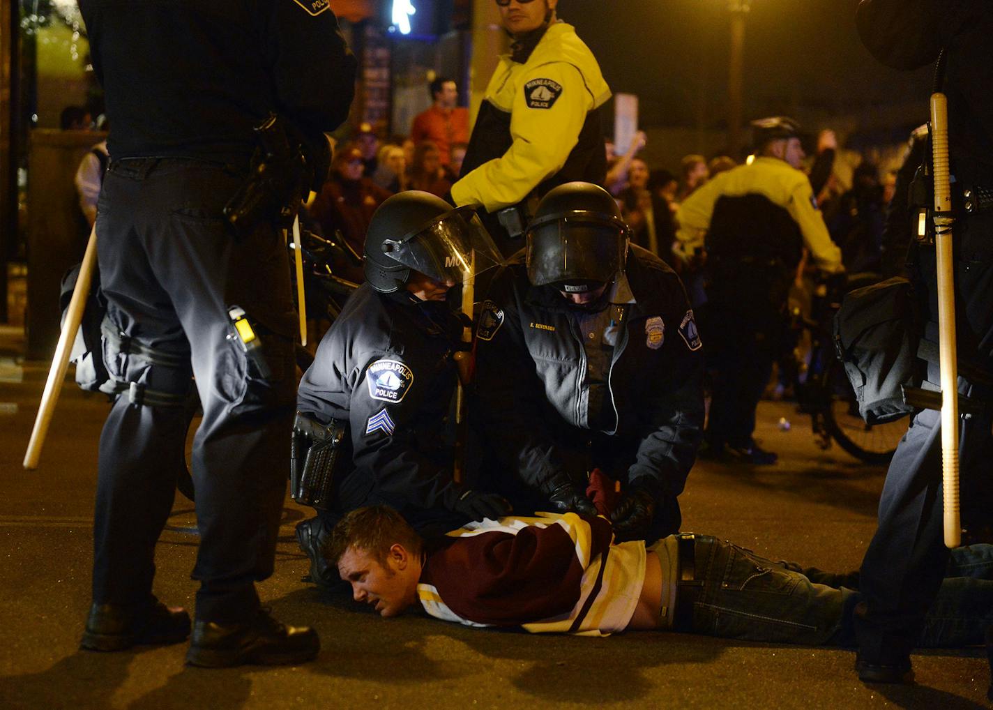 A man is zip-tied by Minneapolis law enforcement during a riot Saturday evening in Dinkytown, Minnesota. Minneapolis Police say 19 people have been arrested after crowds filled the streets of Dinkytown following the Gophers' NCAA hockey title game loss. (AP Photo/The Minnesota Daily, Chelsea Gortmaker) ORG XMIT: MIN2014041412564430