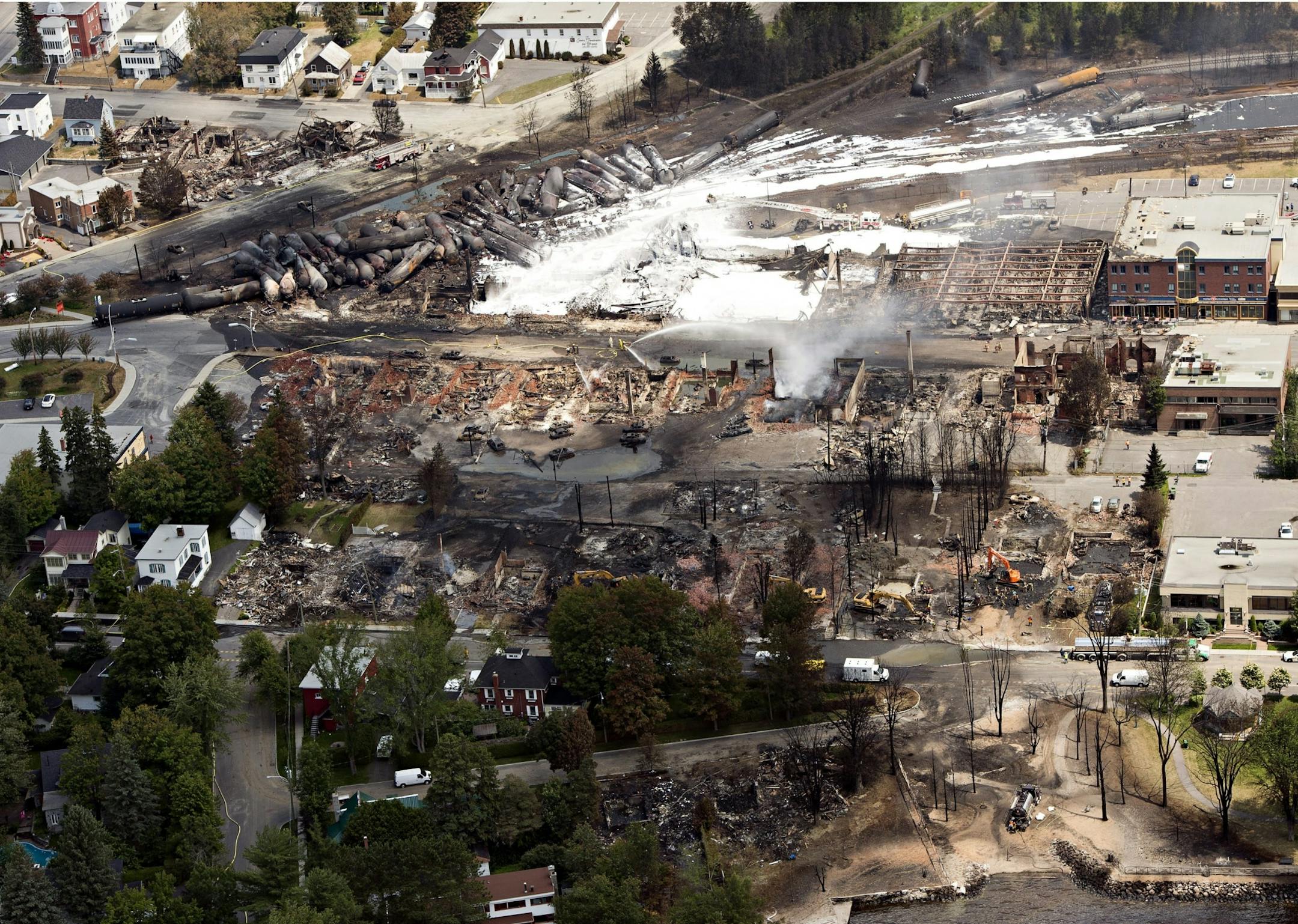 The downtown core lays in ruins as fire fighters continue to water smoldering rubble Sunday, July 7, 2013 in Lac Megantic, Quebec. A runaway train derailed Saturday igniting tanker cars carrying crude oil.