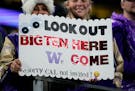 Fans wearing Washington gear held a sign in Seattle referencing Washington’s upcoming move to the Big Ten conference. 