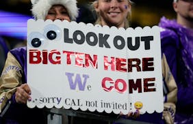Fans wearing Washington gear held a sign in Seattle referencing Washington’s upcoming move to the Big Ten conference.