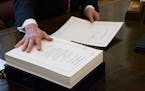 FILE -- President Donald Trump signs the tax reform bill in the Oval Office of the White House in Washington, Dec. 22, 2017. Republicans are pouring g