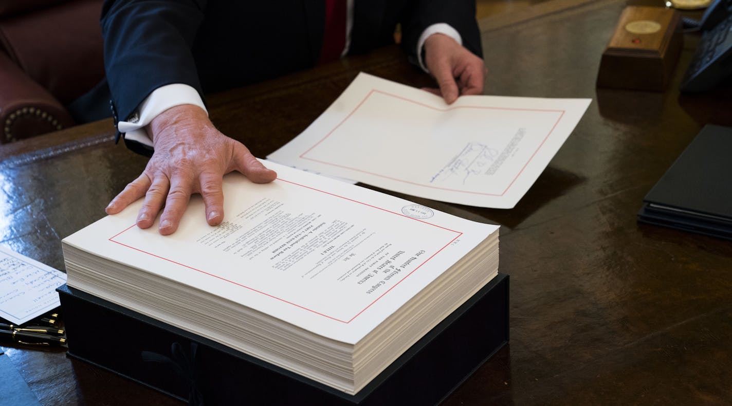 FILE -- President Donald Trump signs the tax reform bill in the Oval Office of the White House in Washington, Dec. 22, 2017. Republicans are pouring government stimulus into a steadily strengthening economy, adding economic fuel at a moment when unemployment is low and wages are beginning to rise, a combination that is stoking fears of higher inflation and ballooning budget deficits. (Doug Mills/The New York Times)