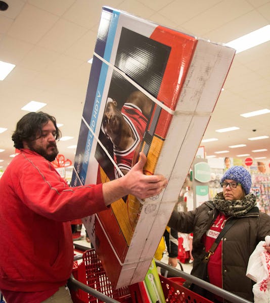 Super Target employee Jeremy Streit helps lift a big screen television into the cart of Tonii Simmons during Thanksgiving night shopping. ] AARON LAVI