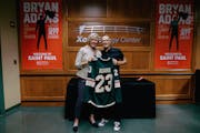 Xcel Energy Center's Kelly McGrath presents rock star Bryan Adams with a Minnesota Wild jersey on July 3, 2023 as they stand backstage in front of con