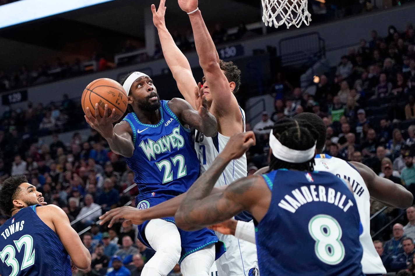 Minnesota Timberwolves guard Patrick Beverley (22) goes up for a shot around Dallas Mavericks center Dwight Powell during the first half of an NBA basketball game Friday, March 25, 2022, in Minneapolis. (AP Photo/Craig Lassig)