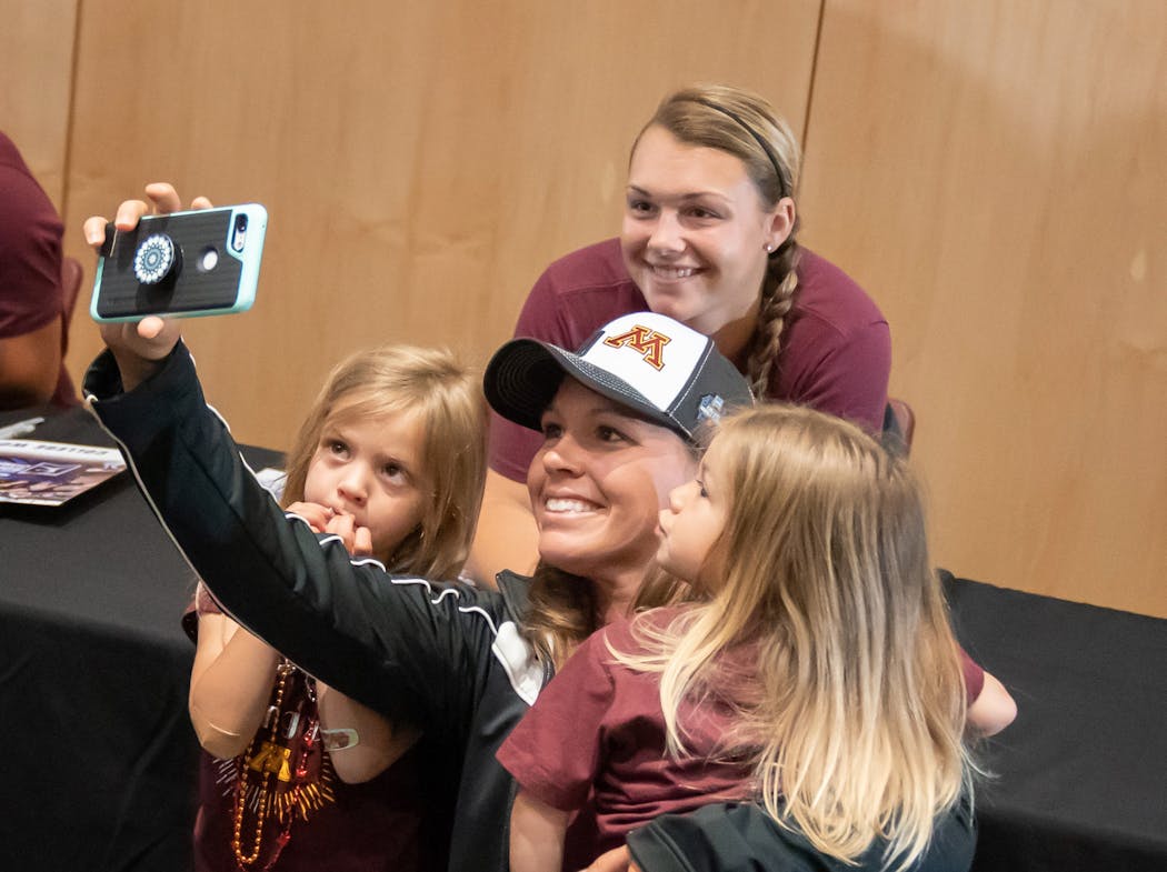 Bethany Loether held up her daughters Lissette, 4, and Loveadah, 2, to take a selfie with Gophers pitcher Amber Fiser during Tuesday’s rally at the Athletes Village.