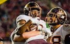 Teammates celebrate with Minnesota wide receiver Le'Meke Brockington (0) after his game-winning touchdown late in the second half of an NCAA college f