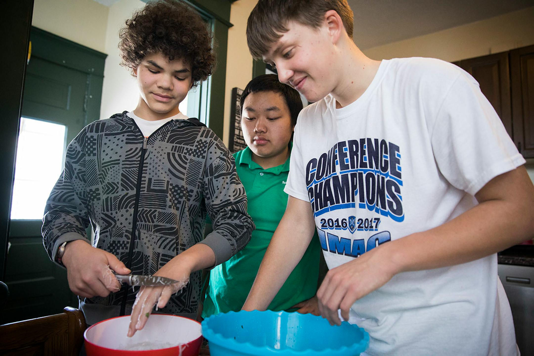 Minnehaha Academy students Daniel Rose, left, 14, and Peter Shaffer, right, 14, cook a traditional Hmong rice noodle dish with the assistance of Bryan Lee, center, while the students are staying at Lee's sister's home in St. Paul. ] LEILA NAVIDI ï leila.navidi@startribune.com BACKGROUND INFORMATION: in St Paul on Wednesday, March 15, 2017. City Stay is an opportunity for Minnesota high school students to do home stays at the homes of other local residents. The cultural exchange program fosters n
