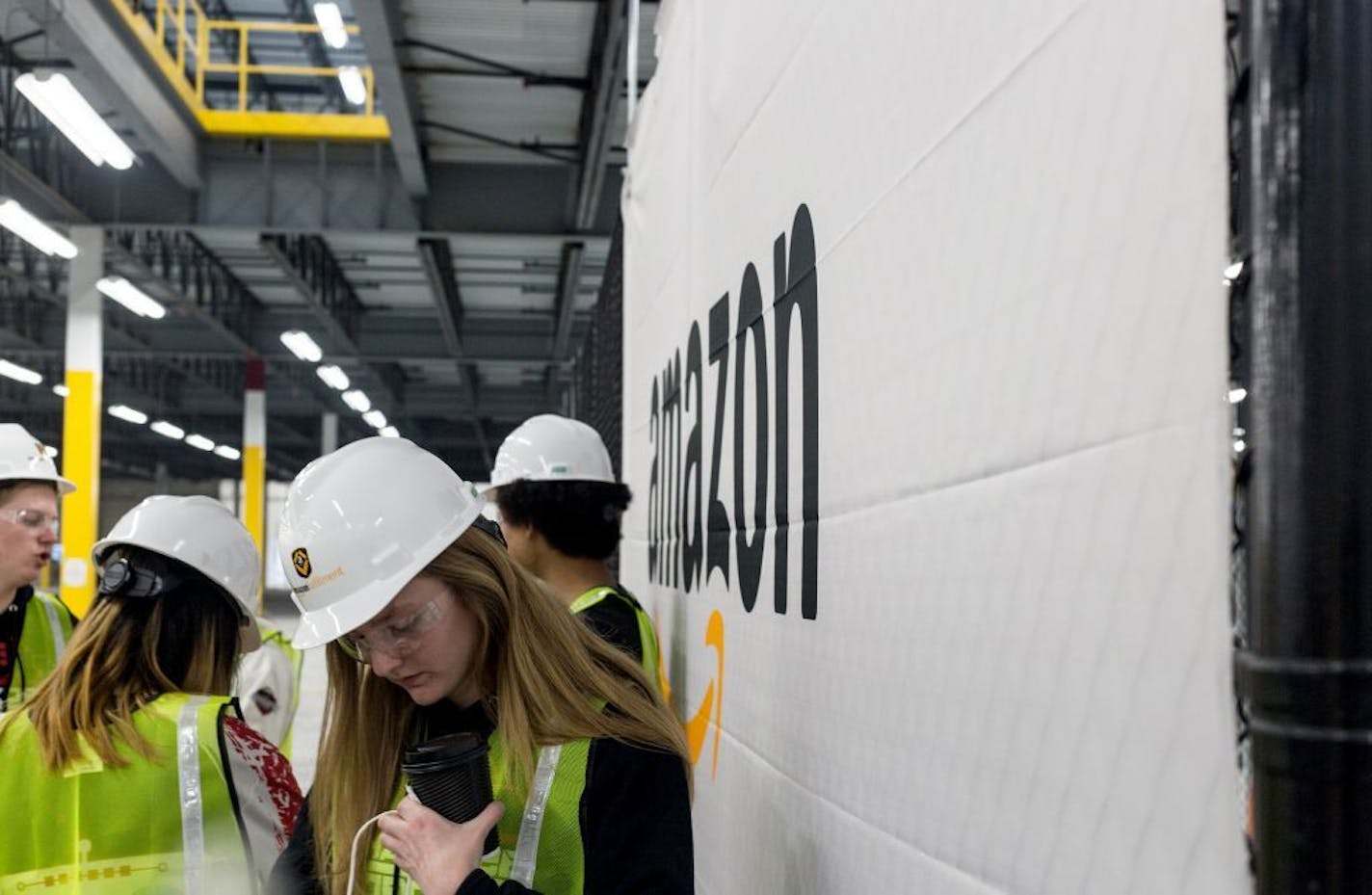 Members of Shakopee Robotics, the Shakopee Senior High School's Robotoic Team, pick up gift bags after displaying their personally designed robots in the not yet open Amazon Shakopee fulfillment center Friday morning. Amazon awarded the robotics team 10,000 dollars.