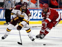 CORRECTS TO MINNESOTA-DULUTH, INSTEAD OF MINNESOTA - Minnesota-Duluth center Adam Johnson, left, and Harvard right wing Tyler Moy chase the puck durin