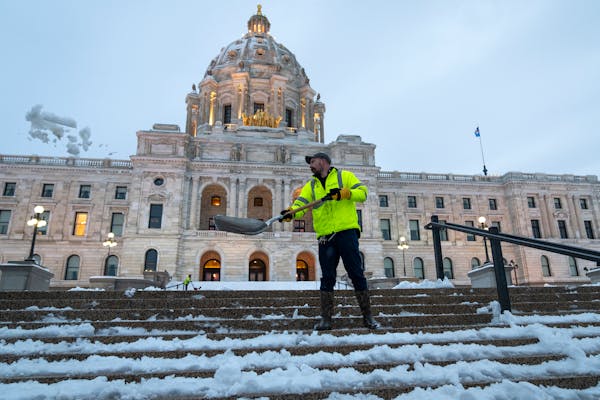 Spencer Miller, with Minnesota Department of Administration Facilities Management, clears the snow off the steps in front of the Minnesota State Capit