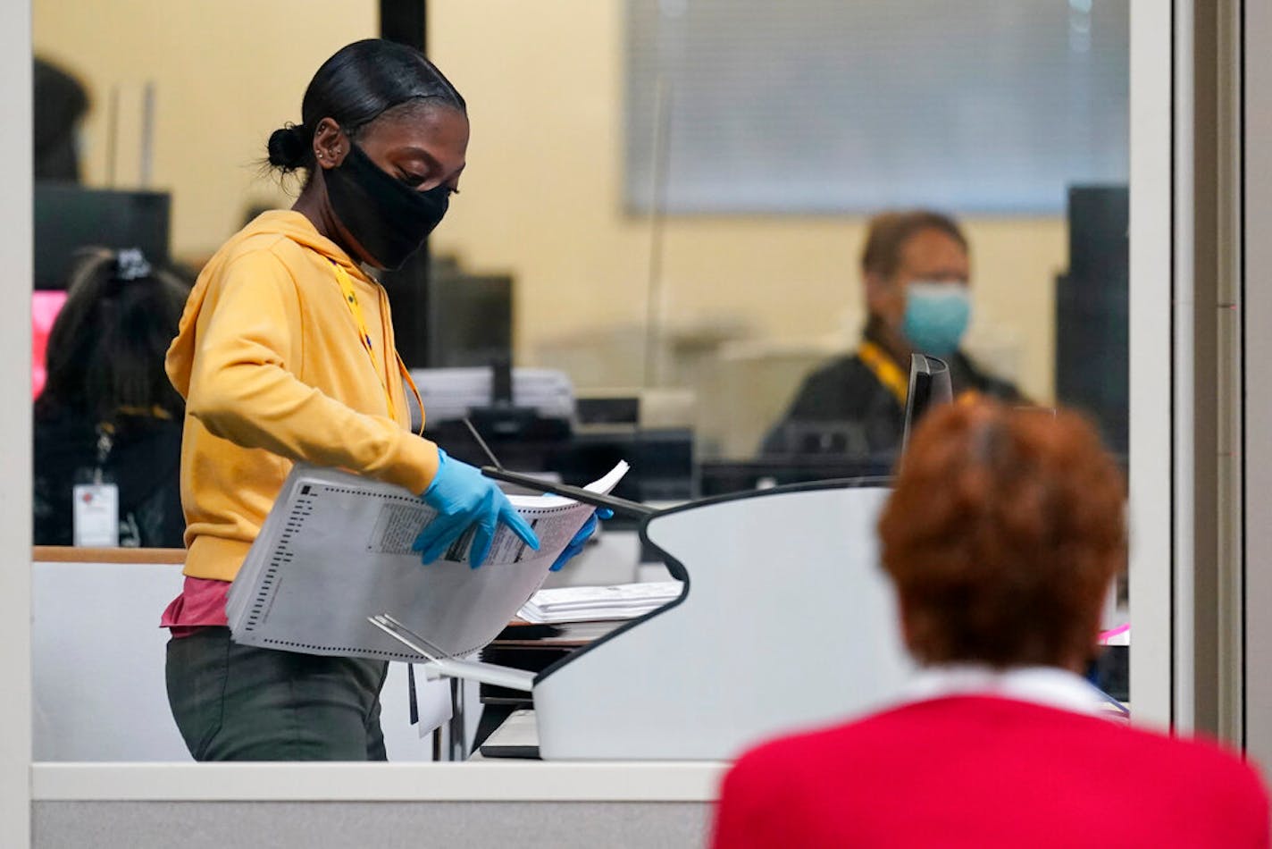 A county election worker scans mail-in ballots at a tabulating area as an observer watches at the Clark County Election Department, Thursday, Nov. 5, 2020, in Las Vegas.