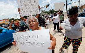 People march outside the Triple S convenience store in Baton Rouge, La., Wednesday, July 6, 2016. Alton Sterling was shot and killed outside the store