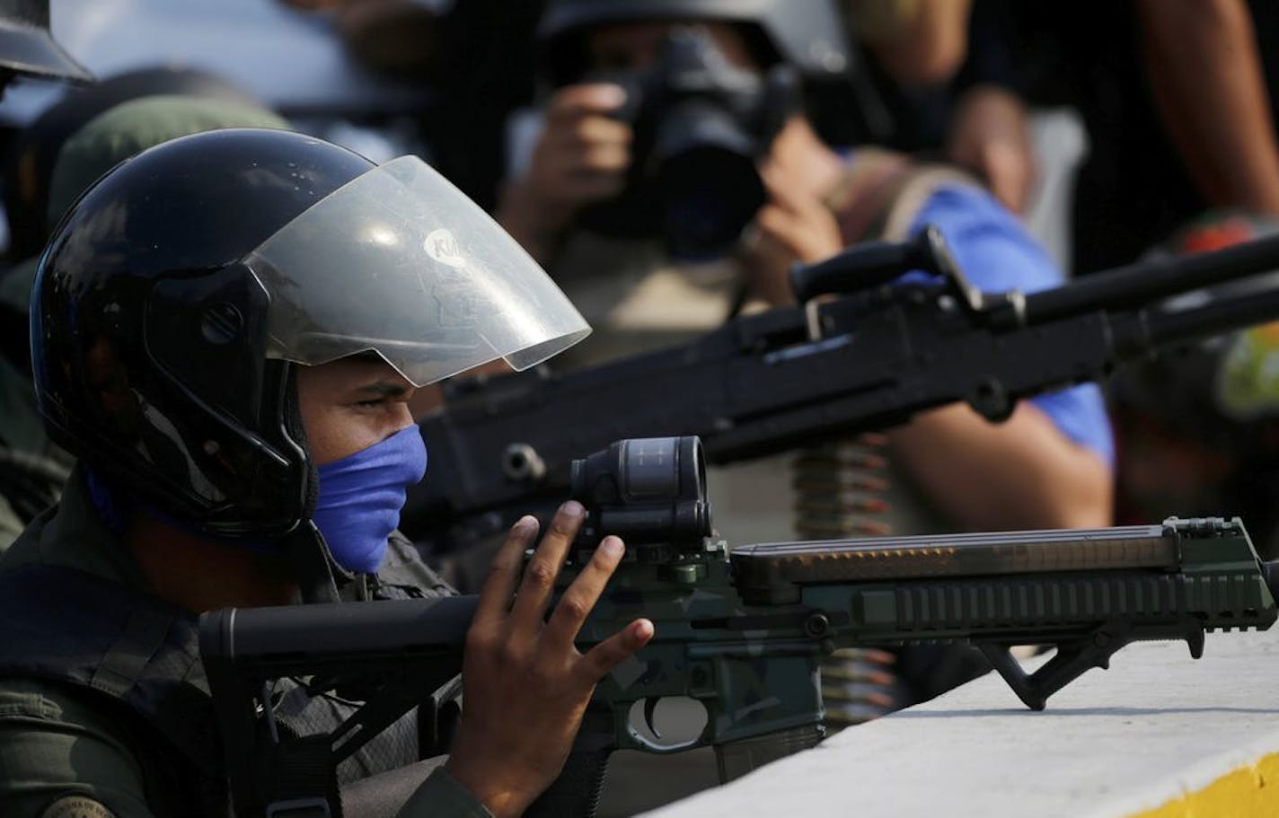 Armed, rebel soldiers who are rising up against the government of Venezuela's President Nicolas Maduro take cover on an overpass outside La Carlota military airbase where loyal troops are located in Caracas, Venezuela, Tuesday, April 30, 2019. Venezuelan opposition leader Juan Guaidó took to the streets with activist Leopoldo Lopez and a small contingent of heavily armed troops early Tuesday in a bold and risky call for the military to rise up and oust socialist leader Nicolas Maduro.