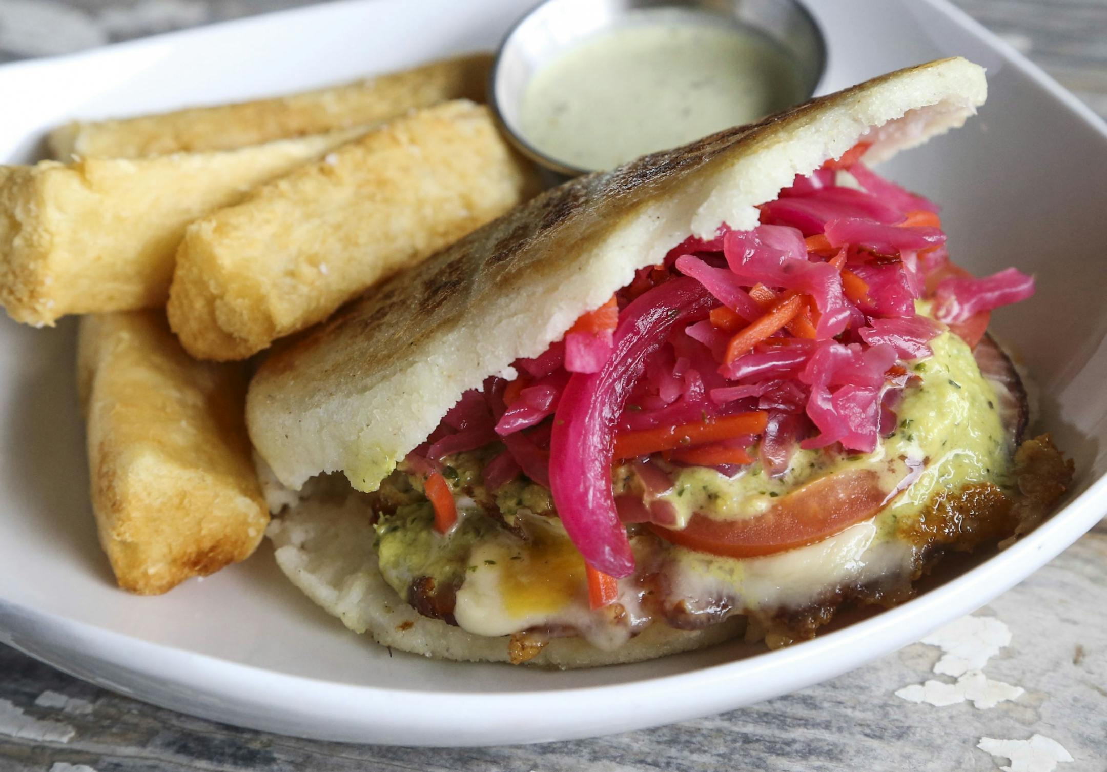 Hola Arepa, one of the city's great food trucks and now a restaurant, and fried egg and ham arepas with tomato, grilled ham and swiss, Hola sauce and pickled cabbage Friday, Sept. 12, 2014, in Minneapolis, MN.