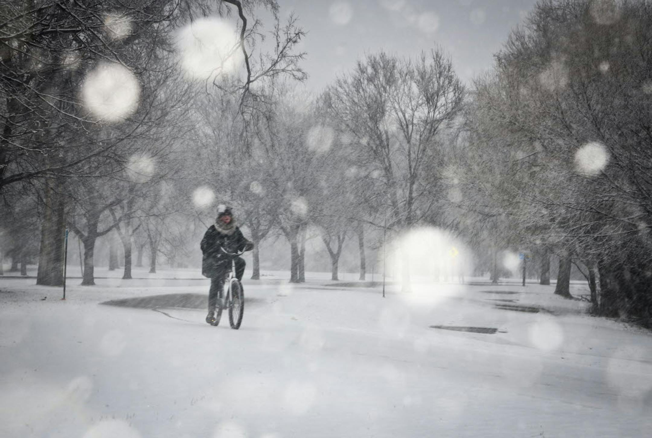 A woman rode her bicycle through the snow around Lake Nokomis in Minneapolis on Monday.