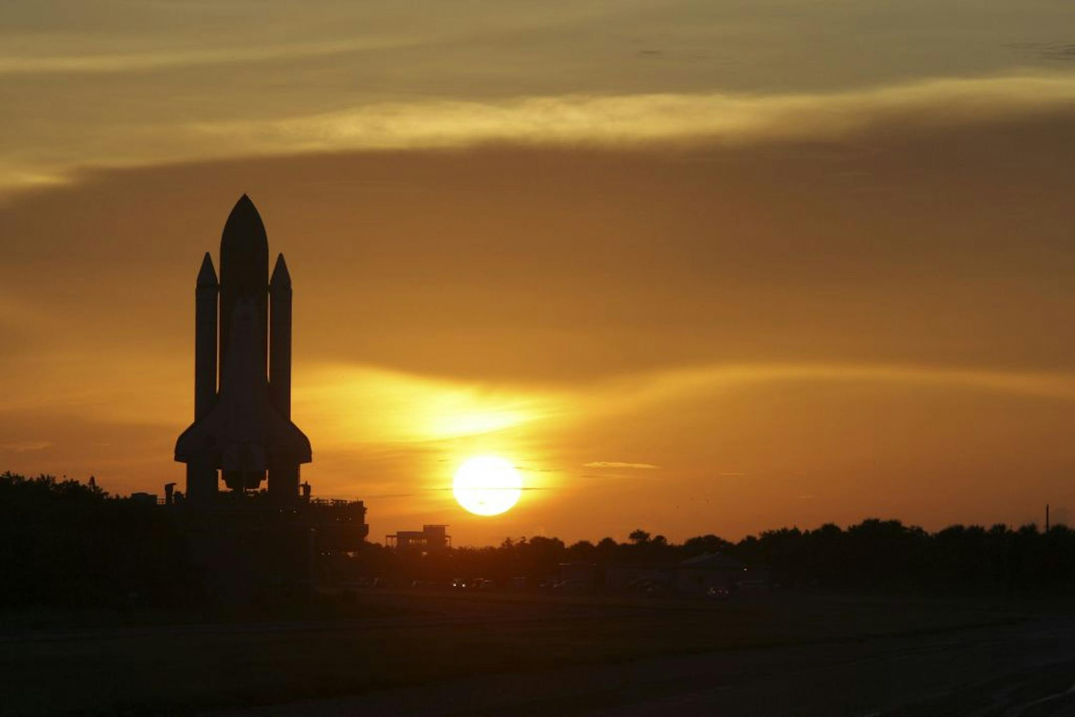 FILE - In this Tuesday, Aug. 4, 2009 file photo, Space shuttle Discovery moves along it's path at sunrise to pad 39A at the Kennedy Space Center in Cape Cananveral, Fla. The space shuttle was sold to America as cheap, safe and reliable. It was none of those. It cost tens of billions of dollars, ended the lives of 14 astronauts and managed to make fewer half the flights promised. Yet despite all that, there were monumental achievements that in the beginning were unforeseen: major scientific advan