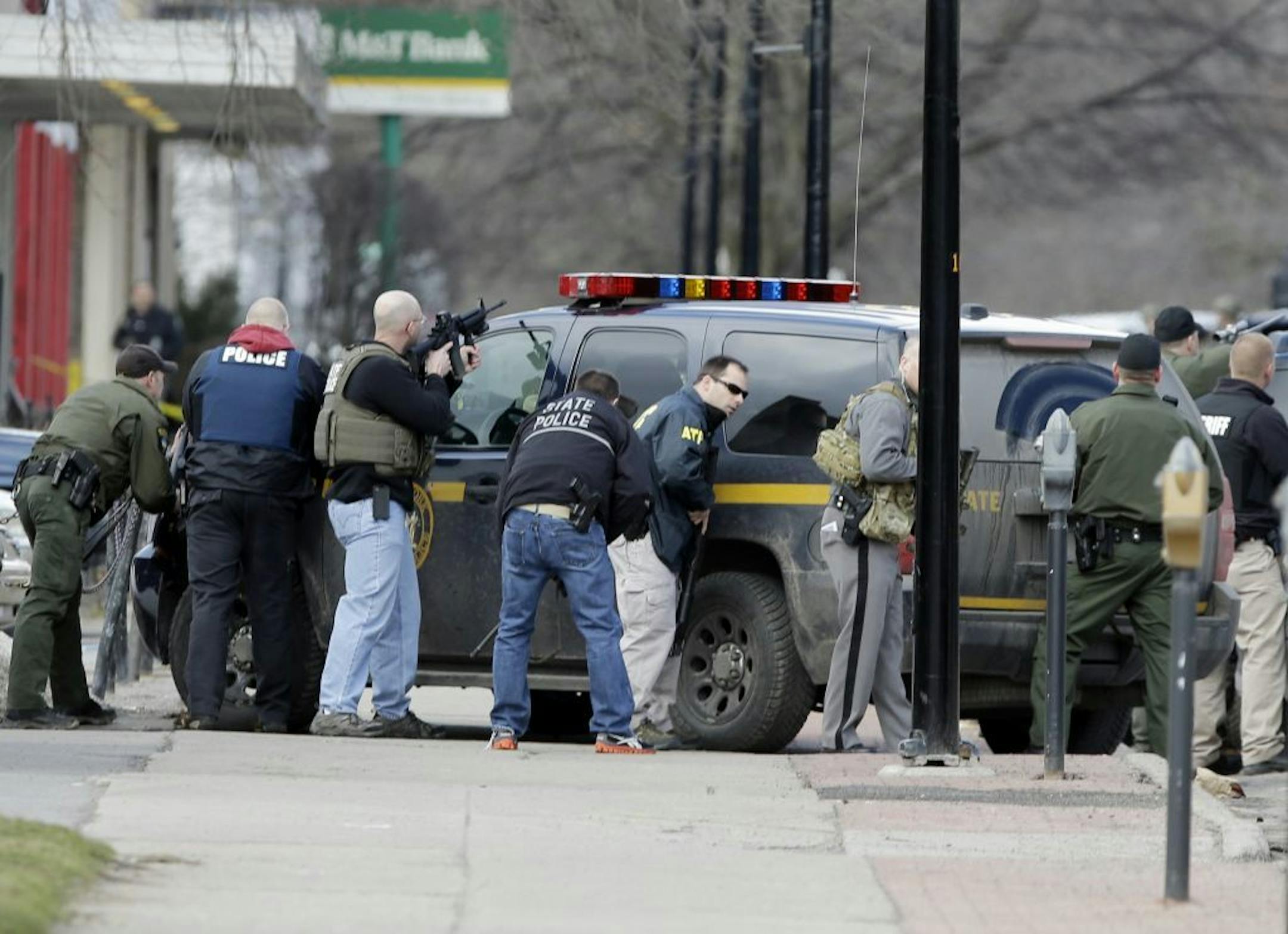 Law enforcement officers take cover along Main Street in Herkimer, N.Y., when shots were fired while they were searching for a suspect in two shootings that killed four and injured at least two on, Wednesday, March 13, 2013. Authorities were looking for 64-year-old Kurt Meyers, said Herkimer Police Chief Joseph Malone. Officials say guns and ammunition were found inside his Mohawk apartment after emergency crews were sent to a fire there Wednesday morning.