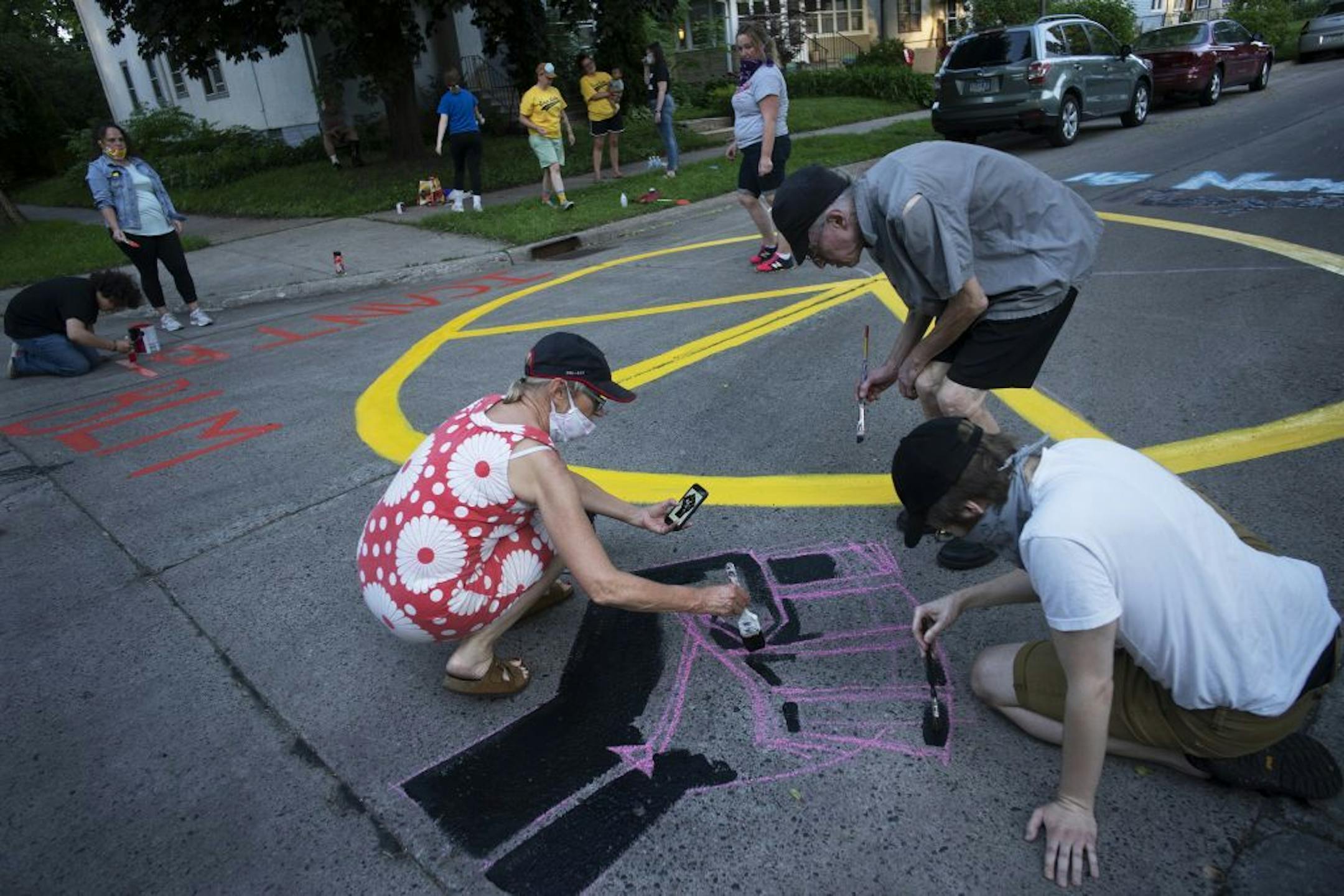 Anne Thompson helps paint a mural on their block intersection to remember what they just went through.