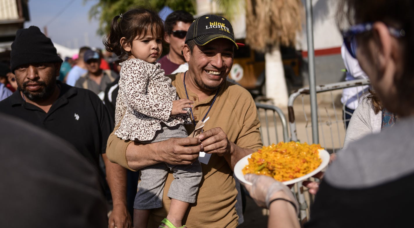 Migrants line up for a food distribution as part of a Christmas Day celebration outside a temporary shelter in Tijuana, Mexico, Sunday, Dec. 23, 2018. Discouraged by the long wait to apply for asylum through official ports of entry, many Central American migrants from recent caravans are choosing to cross the U.S. border wall and hand themselves in to border patrol agents. (AP Photo/Daniel Ochoa de Olza)