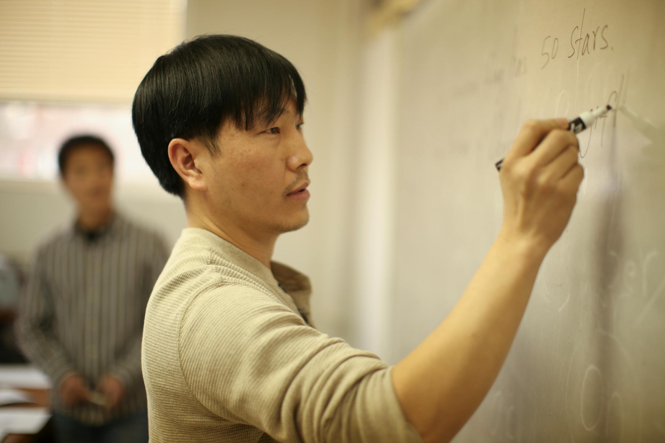 Poua Chang wrote statements about the U.S. on the board during the citizenship class at the Hmong Cultural Center of Minnesota Wednesday afternoon.