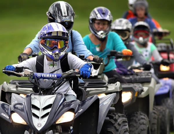 Youthful riders wearing protective gear, lined up in groups that were assigned to various stations at a DNR ATV training course. Stations included obs