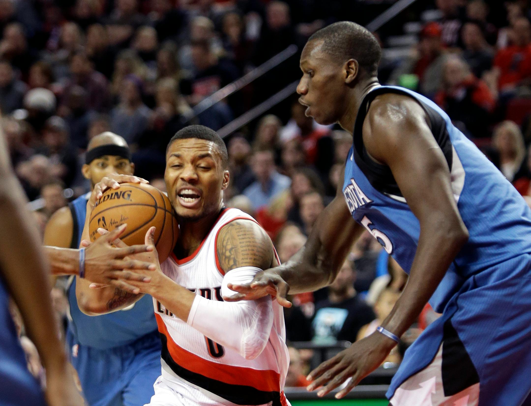 Portland Trail Blazers guard Damian Lillard, left, drives against Minnesota Timberwolves center Gorgui Dieng, from Senegal, during the first half of an NBA basketball game in Portland, Ore., Sunday, Nov. 30, 2014. (AP Photo/Don Ryan)