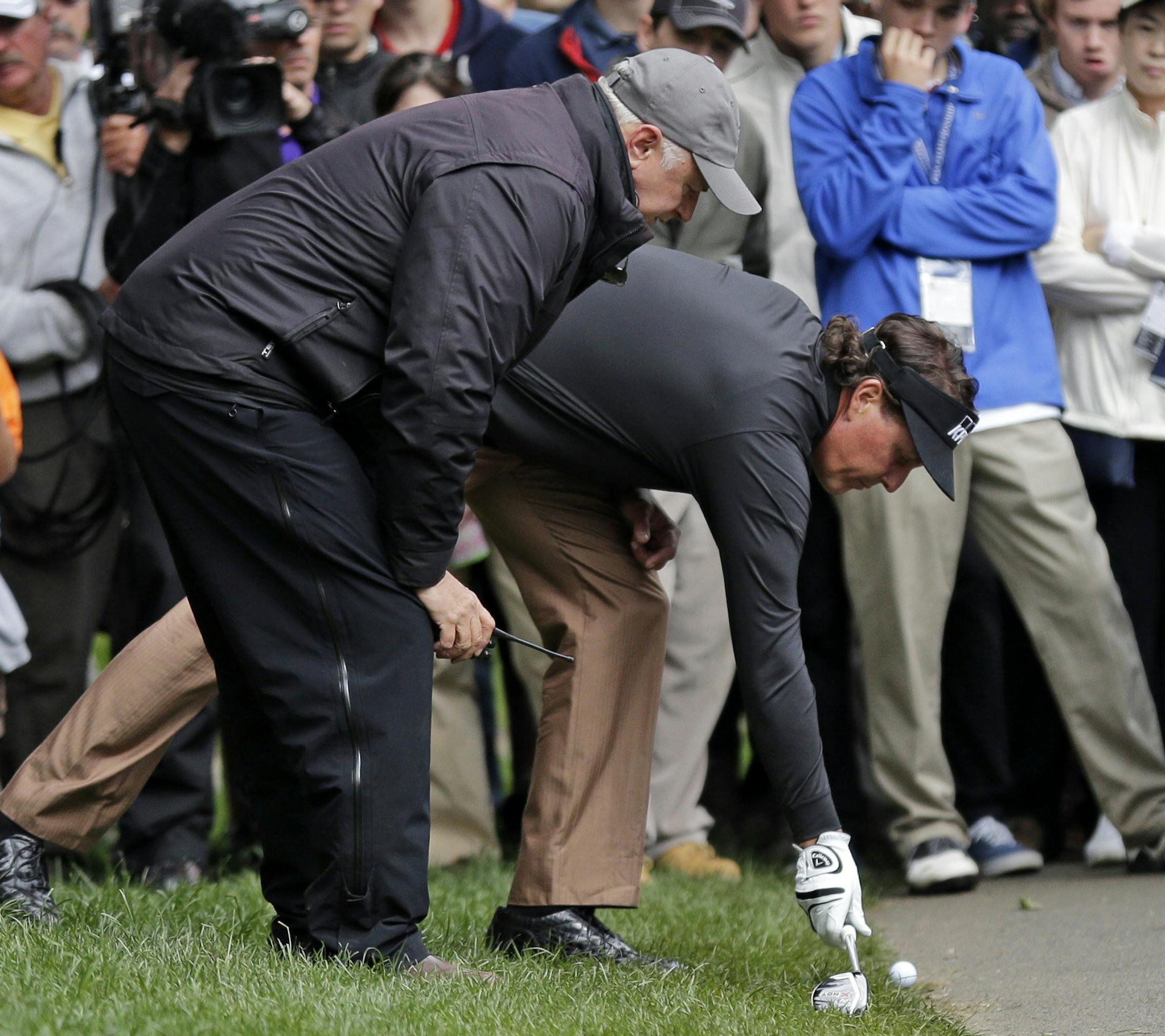 Phil Mickelson gets a ruling from an official after his second shot on the 15th hole during the third round of the Wells Fargo Championship golf tournament at Quail Hollow Club in Charlotte, N.C., Saturday, May 4, 2013. (AP Photo/Chuck Burton)