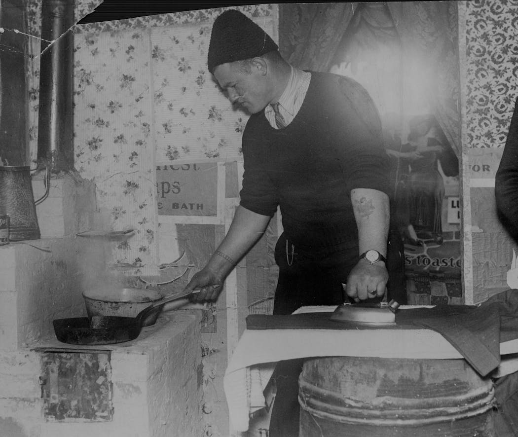 A resident of Rooseveltville demonstrated cooking and ironing in his shanty near Nicollet Island in 1933.