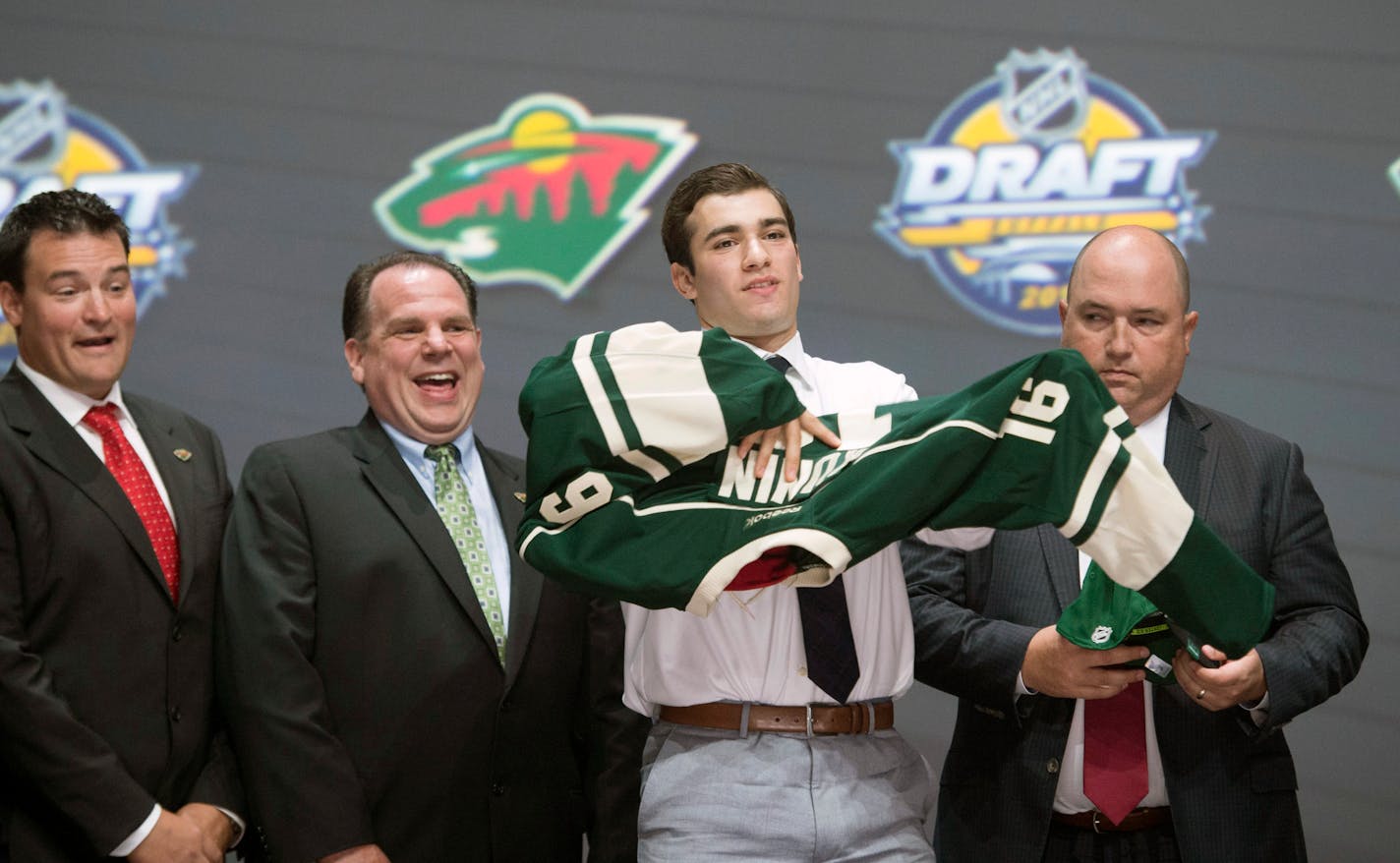 Luke Kunin, second from right, puts on his sweater as he stands with members of the Wild management team at the NHL draft in Buffalo, N.Y., Friday June 24, 2016.