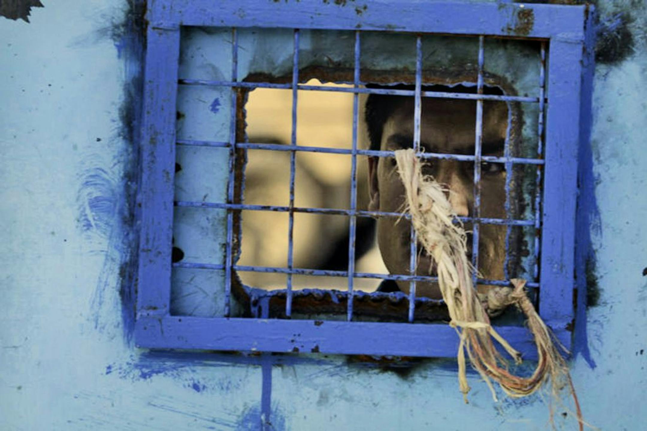 FILE - In this Monday, April 25, 2011 file photo, a prisoner looks out of his cell window at the main prison in Kandahar, Afghanistan. The United Nations said Sunday that Afghan authorities were still torturing prisoners, such as hanging them by their wrists and beating them with cables. Particularly in the southern province of Kandahar, the U.N. received reports that authorities were using unofficial sites to torture detainees before transporting them to the regular prison.