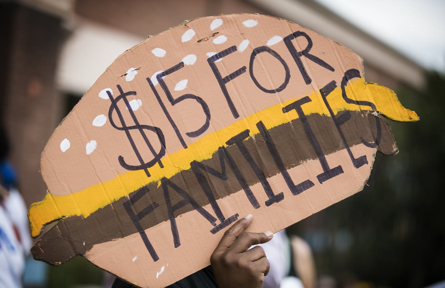 A man holds a sign shaped like a cheeseburger during a rally and march supporting $15 minimum wage on W. Broadway Avenue. ] (Leila Navidi/Star Tribune) leila.navidi@startribune.com BACKGROUND INFORMATION: Activists supporting a $15 minimum wage rally and march outside corporate fast food restaurants, payday lenders and a bank on W. Broadway Avenue in north Minneapolis on Monday, September 12, 2016. The activists are pushing for an ordinance passage at City Hall this year for a $15 minimum wage i