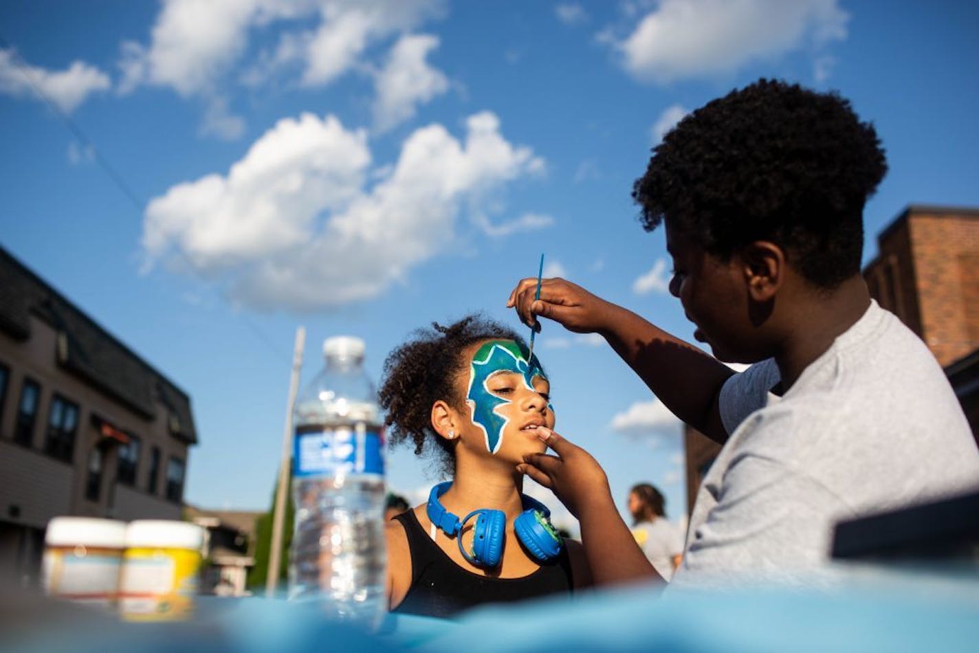 Kimora Jackson, 11, gets her face painted by Ronnisha Tolbert during National Night Out block parties in the Folwell neighborhood.