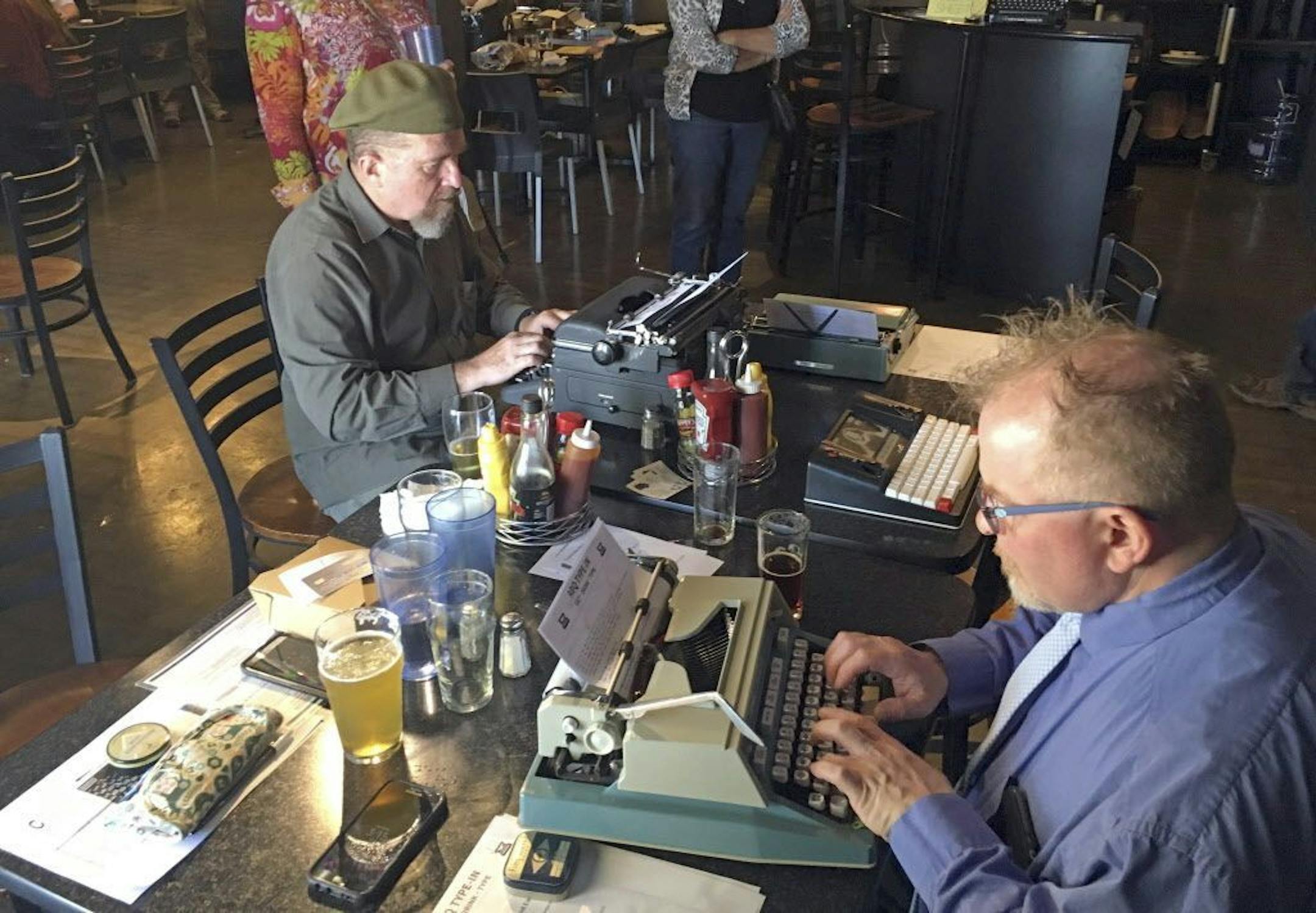 In this April 23, 2017 photo, Joe Van Cleave, left, and Rich Boucher, right, try out various vintage typewriters at a "type-in" in Albuquerque, N.M. "Type-ins" are social gatherings in public places where typewriter fans test different vintage machines. The vintage typewriter is making a comeback with a new generation of fans gravitating to machines that once gathered dust in attics and basements across the country.