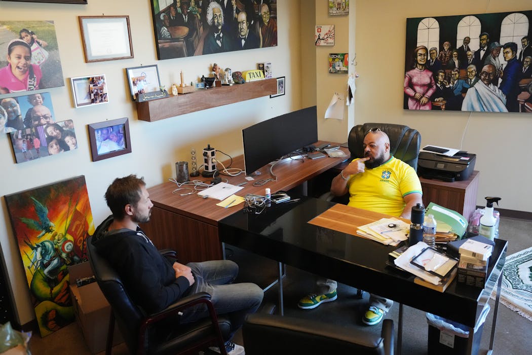 Waleed Sonbol, co-owner and CEO of Blue & White Taxi, talks with customer service manager Jeremy Kramer, left, in his office Wednesday at Blue & White Cab in St. Louis Park.
