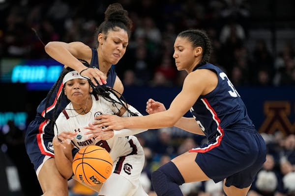 South Carolina's Destanni Henderson is fouled as she drives between UConn's Olivia Nelson-Ododa, right, and Azzi Fudd during the second half
